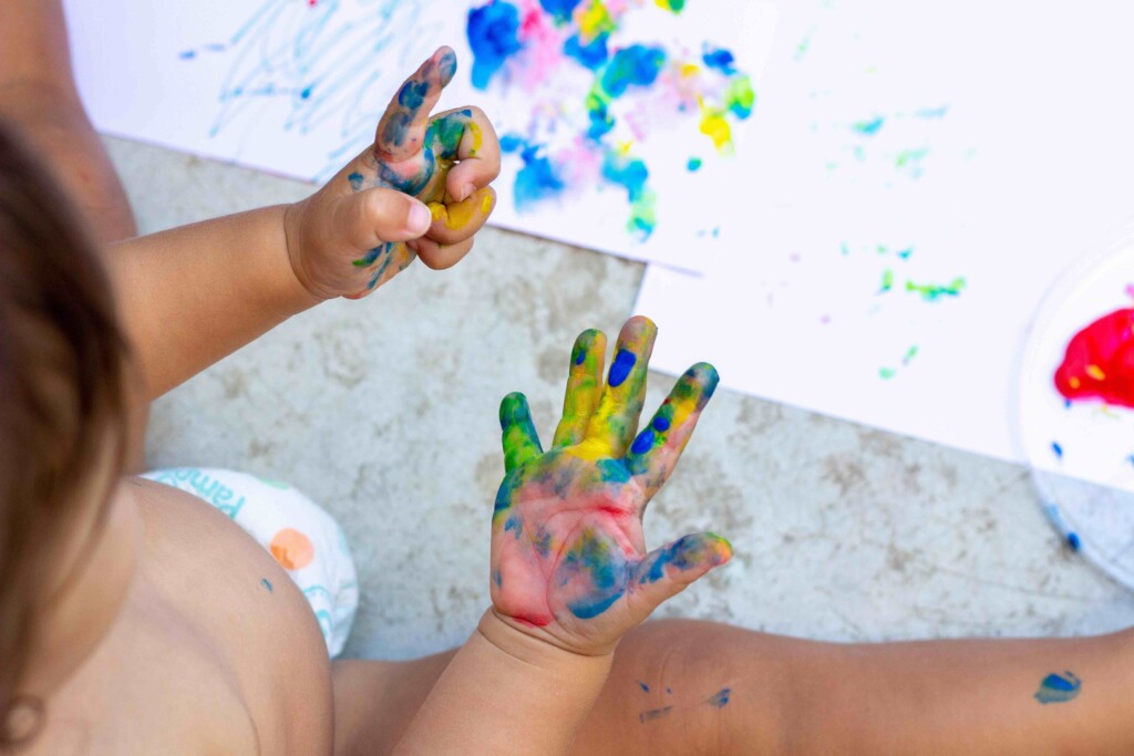 a baby looking at paint on their hands